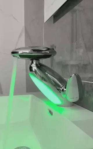 Chrome pull-out LED bathroom faucet with green mood light installed on a countertop basin.