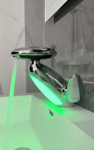 Chrome pull-out LED bathroom faucet with green mood light installed on a countertop basin.