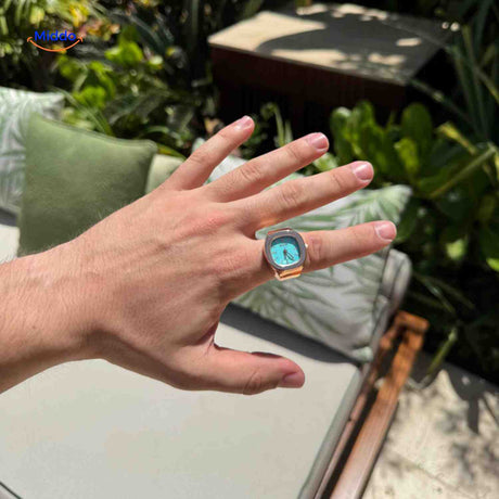Rose gold ring watch with mint green dial worn on hand.