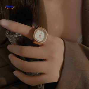Rose gold ring watch with white square dial on hand.