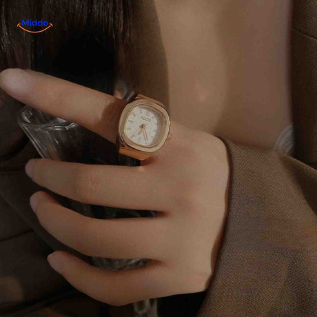 Rose gold ring watch with white square dial on hand.