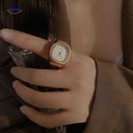 Rose gold ring watch with white square dial on hand.