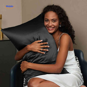 Black satin pillowcase on pillow reducing hair breakage.