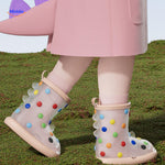 Shark rain boots paired with pink rain jacket, colorful and fun kids' outdoor gear.