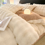 White plush bedding set with soft fabric and bedroom lighting.