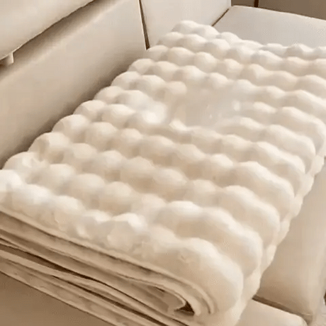 Beige plush furniture cover neatly folded for compact storage and easy transport.