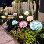 Solar flower lantern illuminating garden pathway with soft hydrangea blooms.