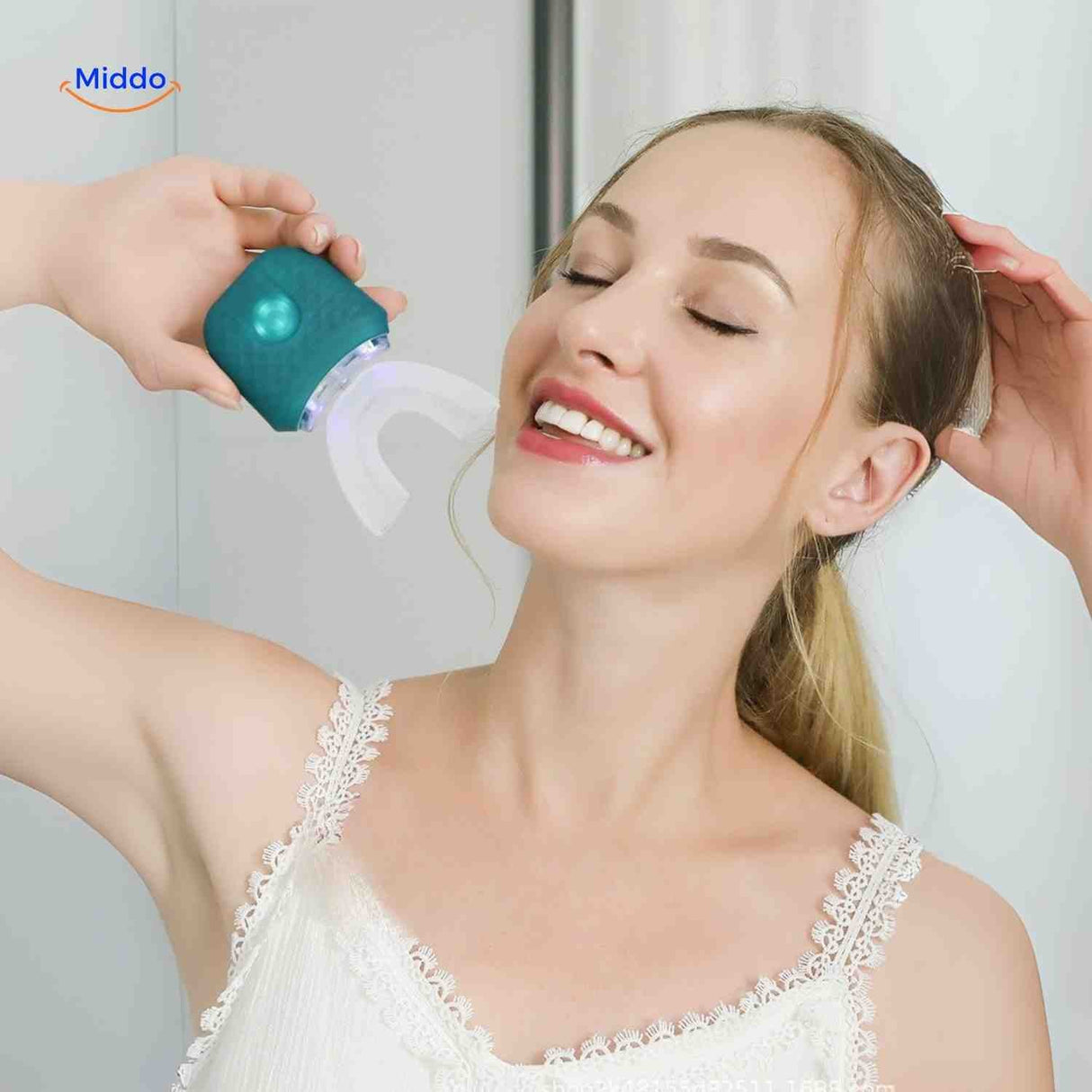 Green sonic electric toothbrush in use with blue light whitening function activated.