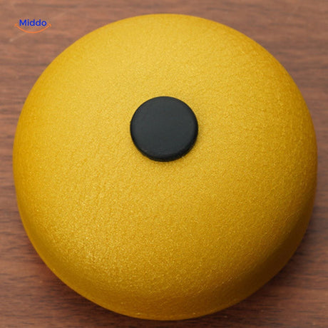 Yellow steel tongue drum with tuned number markers on playing surface.