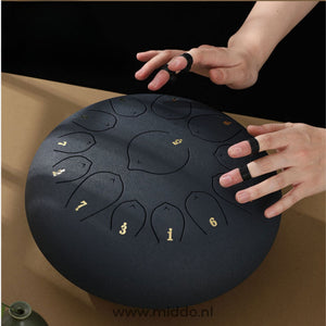 Black steel tongue drum being played with mallets in use.