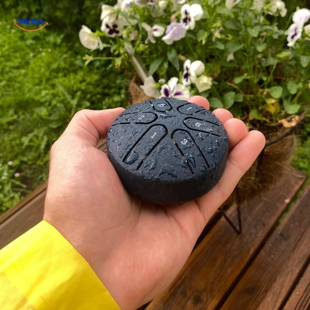Water-resistant steel tongue drum in rain showcase outdoor durability.