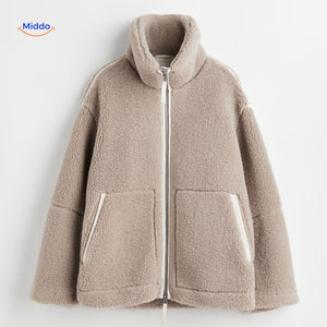 Beige teddy wool coat fabric closeup highlighting soft texture and construction.