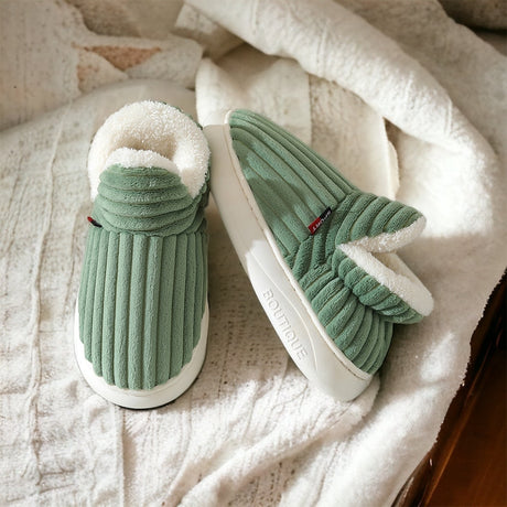 Green therapeutic slippers displayed on a white surface, highlighting their cozy aesthetic.