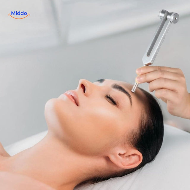Healing tuning fork used in sound therapy facial treatment for vibration wellness.