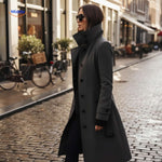 Woman walking in grey Veloura button-front coat on city street.