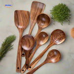 Wooden cooking spoons and spatulas displayed on kitchen table showing full set variety.