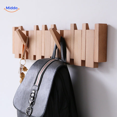 Handmade wooden piano coat rack with coats and bags organized on foldable hooks.